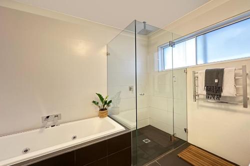 a bathroom with a tub and a glass shower at The Bronte Breeze in Sydney