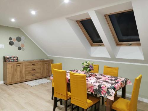 a dining room with a table and yellow chairs at Stara Stolarnia in Ruciane-Nida