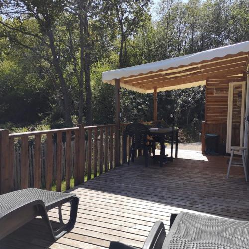 une terrasse en bois avec une table et une pergola dans l'établissement Mobil Home 6 personnes de 41m2 dans camping 4 étoiles, à Bidart