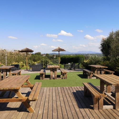 un groupe de tables de pique-nique en bois et de parasols dans l'établissement Mobil Home 6 personnes de 41m2 dans camping 4 étoiles, à Bidart