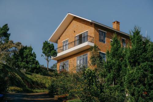 a brick house with a balcony on a hill at SEN VILLA Boutique in Bao Loc