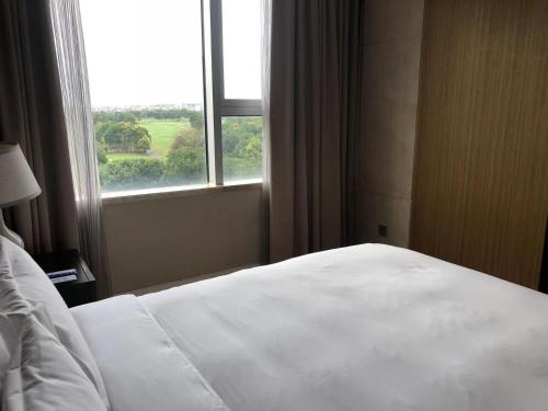 a bedroom with a white bed and a window at Crowne Plaza Shanghai Anting-Auto City - 15 Minutes drive to F1 in Jiading