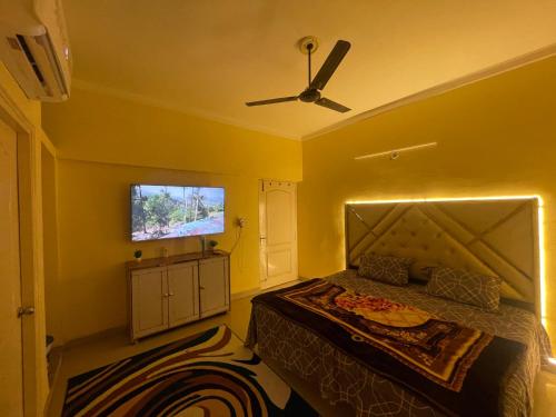 a yellow bedroom with a bed and a ceiling fan at Mannat Manzil in Lucknow