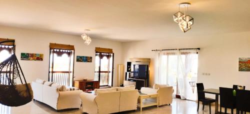 a living room with white furniture and windows at Jabal Sifah Tha Marina View Apartment in Muscat