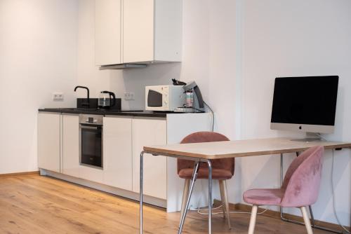 cocina con escritorio, ordenador y 2 sillas en Apartment mit Parkblick & Massagestuhl, en Leipzig