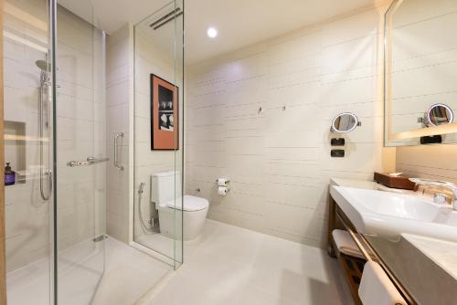 a bathroom with a shower and a toilet and a sink at Eastin Grand Hotel Sathorn in Bangkok