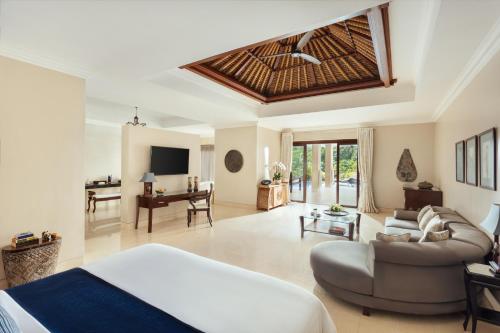 a room with a bed and a couch and a table at Viceroy Bali in Ubud