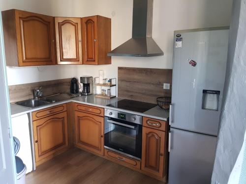 a kitchen with wooden cabinets and a stainless steel refrigerator at Au jardin de Victor in Saint-Rémy-en-Bouzemont-Saint-Genest-et-Isson