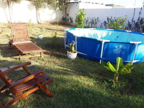 eine blaue Badewanne im Hof mit einem Stuhl und einer Bank in der Unterkunft Charmante maison de campagne in Temara