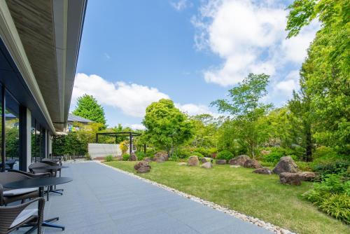 a patio with tables and chairs in a garden at Hotel Okura Kyoto Okazaki Bettei in Kyoto