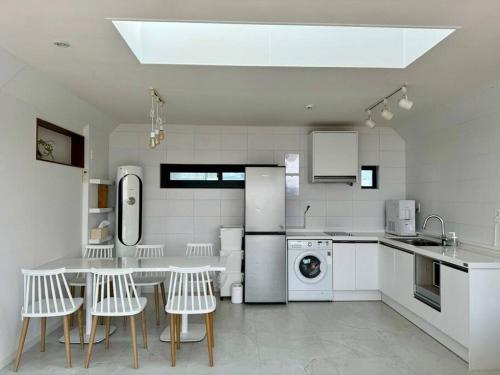 a white kitchen with a table and chairs in it at Sunyeonchae in Jeju
