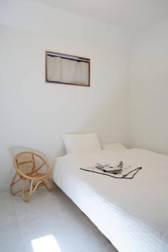 a white room with a bed and a chair at Sunyeonchae in Jeju