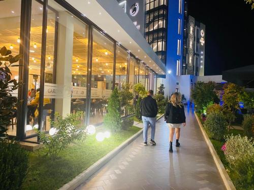 a man and woman walking down a sidewalk in front of a store at Grand White City Hotel in Berat