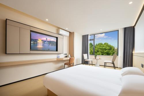 Habitación de hotel con cama y TV de pantalla plana. en MISONG Light Residence Design Hotel - Shangrao Wuyuan Landscape Bridge, en Wuyuan