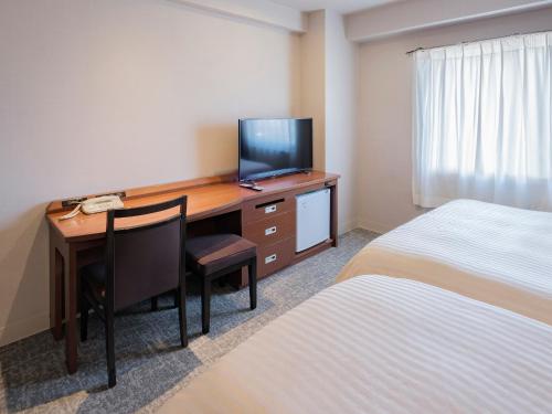 a hotel room with a desk with a television and a bed at Vessel Hotel Miyakonojo in Miyakonozyō