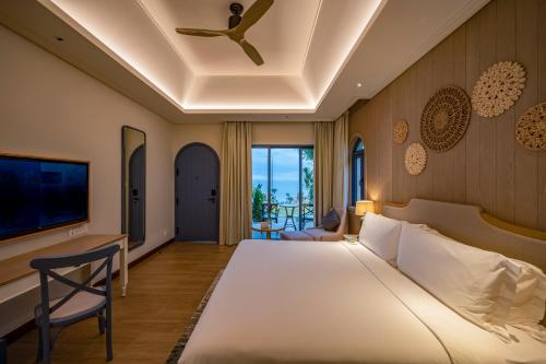 a bedroom with a large bed with a ceiling fan at Centara Mirage Resort Mui Ne in Mui Ne