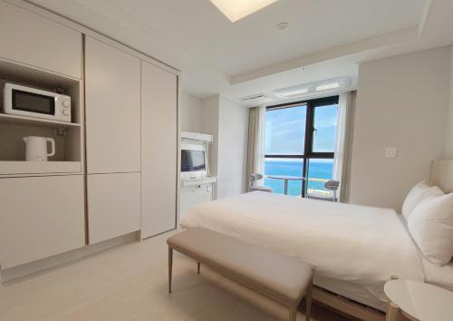 a white bedroom with a large bed and a window at UH FLAT The SOKCHO in Sokcho