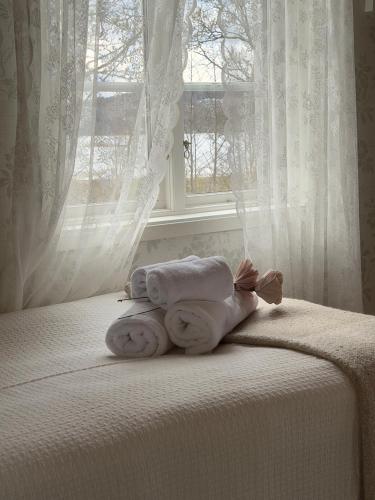 a pile of towels sitting on a bed in front of a window at Hällesdalens Gård - semesterhus i Bohuslän in Svenshögen