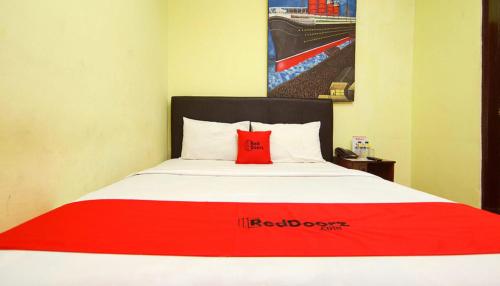 uma cama com uma almofada vermelha em cima em The Legian 777 em Legian