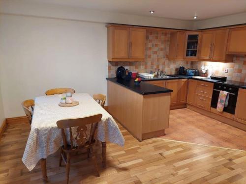 una cocina con mesa y una cocina con armarios de madera. en 5 Sruthan Beag Dingle, en Dingle