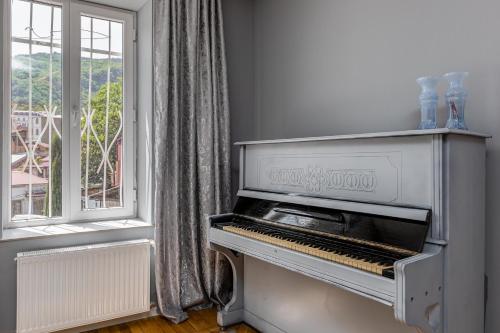 a white piano in a room with a window at MaRKoS Sololaki Flat in Tbilisi City