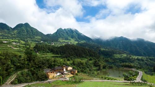una casa en una colina con un río y montañas en Dayong Antique Feature Resort, en Zhangjiajie