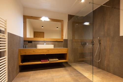 a bathroom with a sink and a shower with a mirror at Platterhof in Tirolo