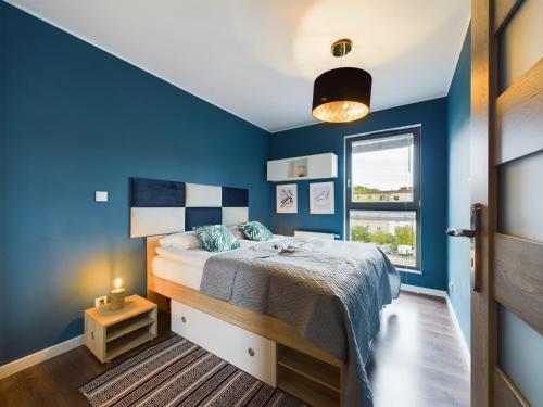 een blauwe slaapkamer met een bed en een raam bij Browar Gdański One Bedroom Apartments with Free Parking by Renters in Gdańsk