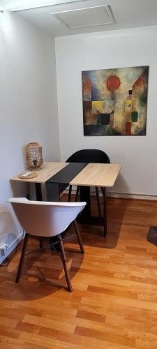 une table et des chaises dans une pièce avec un tableau dans l'établissement Le Nid d'Anatole, au Mans