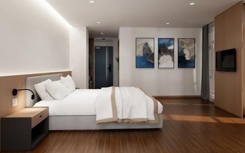 sypialnia z białym łóżkiem i obrazami na ścianie w obiekcie River Way Hotel w Ha Long