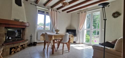 sala de estar con mesa y chimenea en Gîte Le Clos des Vosges, en Ban-sur-Meurthe-Clefcy