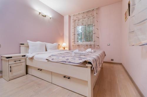 a white bedroom with a large bed and a window at Elegant 1-Bedroom Apartment in Plovdiv