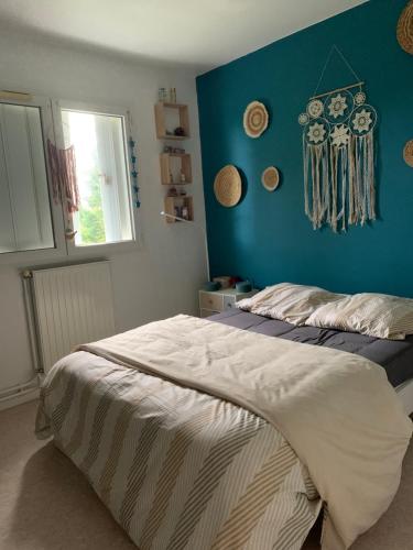 une chambre avec un lit avec un mur bleu dans l'établissement Appartement ensoleillé, à La Teste-de-Buch