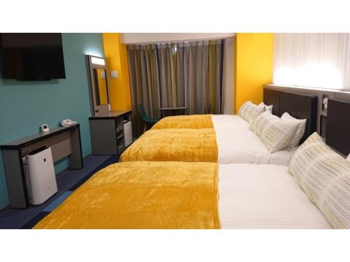 2 łóżka w pokoju hotelowym z żółtymi ścianami w obiekcie Green Rich Hotel Okinawa Nago - Vacation STAY 49879v w mieście Nago