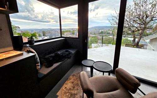 Edge Oslo - Hideaway with Breathtaking City Views في أوسلو: غرفة معيشة مع نافذة كبيرة وأريكة وكراسي