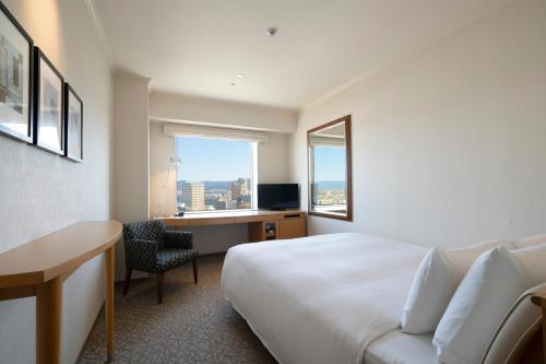 a hotel room with a bed and a desk and a window at Hotel Associa Toyohashi in Toyohashi