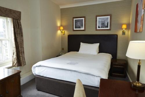a hotel room with a large bed and a desk at George Hotel by Greene King Inns in Huntingdon