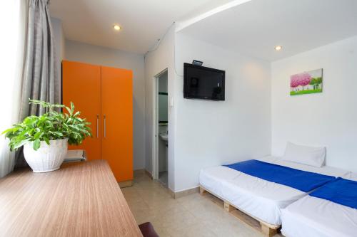 um quarto com uma cama e uma televisão na parede em Ehome Saigon - Gạo hostel em Ho Chi Minh