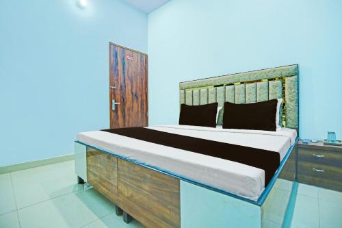 1 dormitorio con 1 cama grande y cabecero de madera en OYO Sirsa Hotel & Guest House, en Sirsa