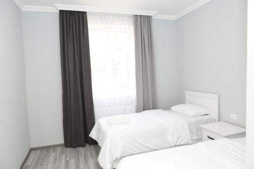 a white room with two beds and a window at VST KHANOYAN'S HOTEL in Ninotsminda