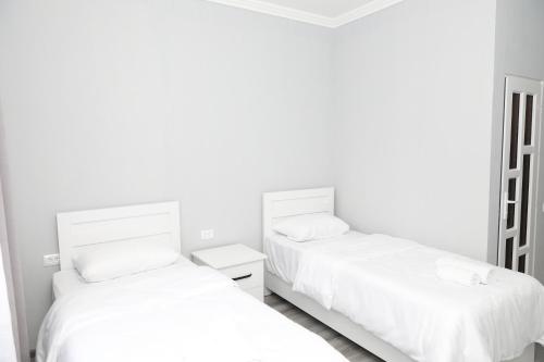 two beds in a room with white walls at VST KHANOYAN'S HOTEL in Ninotsminda