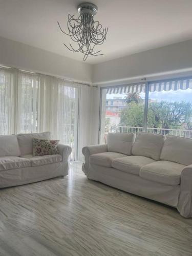 - un salon avec deux canapés blancs et une grande fenêtre dans l'établissement Les Oliviers Big Terrace&Pool Comfy, à Roquebrune-Cap-Martin