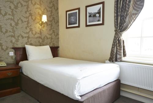 a bed in a hotel room with a window at George Hotel by Greene King Inns in Huntingdon