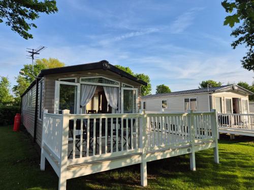 un mobile home avec une terrasse couverte et une maison dans l'établissement Caravan at Seton Sands, near Edinburgh and Berwick, à Port Seton