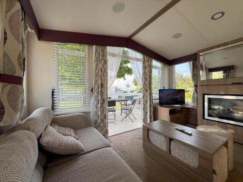un salon avec un canapé, une table et une télévision dans l'établissement Caravan at Seton Sands, near Edinburgh and Berwick, à Port Seton