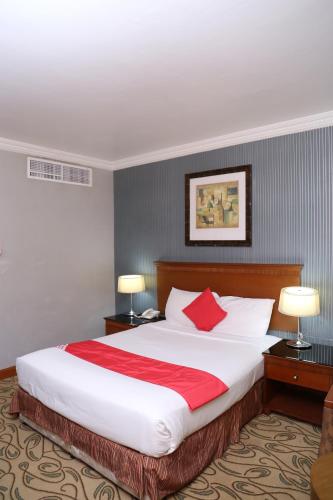 a hotel room with a large bed with red pillows at City Plaza Hotel in Fujairah