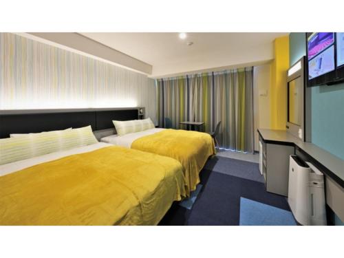 Green Rich Hotel Okinawa Nago - Vacation STAY 49889v في ناغُو: غرفة فندقية بسريرين وتلفزيون بشاشة مسطحة