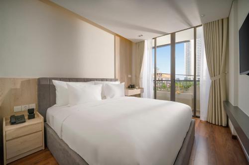 1 cama blanca grande en una habitación con ventana en Tashi Ocean Hotel & Apartment Da Nang en Da Nang