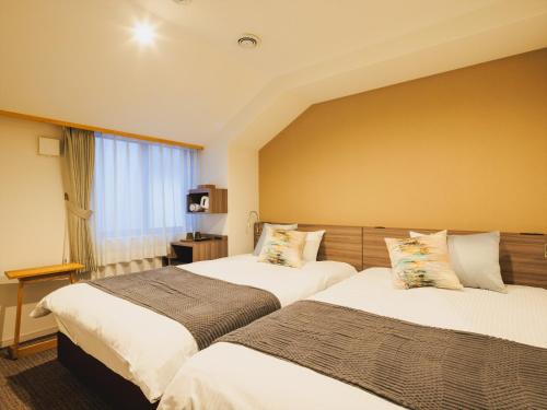 a hotel room with two beds and a window at Giappo Franca Kyoto in Kyoto