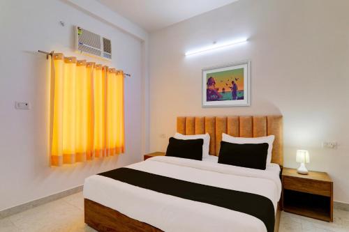 a bedroom with a large bed and a yellow curtain at OYO Flagship Samar palace in Bāra Banki